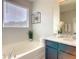 Relaxing bathroom featuring a soaking tub, vanity with granite countertop, and a large window at 8039 Oak Shadow Ct, Davenport, FL 33837
