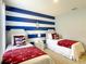 Nautical themed bedroom with twin beds, striped wall, and charming nautical decor at 8039 Oak Shadow Ct, Davenport, FL 33837