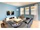 Stylish living room with blue walls, a comfortable sectional sofa, and large windows with sheer curtains at 8039 Oak Shadow Ct, Davenport, FL 33837