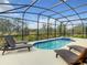 Serene screened-in pool area with lounge chairs, lush landscaping, and clear blue skies at 8039 Oak Shadow Ct, Davenport, FL 33837