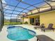 Picturesque pool area featuring a screened-in enclosure, comfortable lounge chairs, and a sparkling pool at 8039 Oak Shadow Ct, Davenport, FL 33837