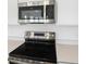 Close up of stainless steel microwave and electric range stove top surrounded by white cabinets at 816 Lake Dell Rd, Dundee, FL 33838