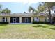 Backyard of home featuring a green lawn, hedges, and screened patios at 127 Club Villas Ln, Kissimmee, FL 34744