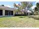 Backyard featuring a green lawn, trimmed hedges, and screened patios at 127 Club Villas Ln, Kissimmee, FL 34744