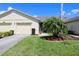 Well-manicured lawn with charming landscaping and a view of a one-car garage at 127 Club Villas Ln, Kissimmee, FL 34744