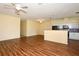 A spacious living room featuring laminate wood flooring and views of the kitchen and hallway at 127 Club Villas Ln, Kissimmee, FL 34744