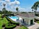 Inviting community pool surrounded by lush tropical landscape, and a sunny pool house at 127 Club Villas Ln, Kissimmee, FL 34744