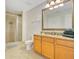 Bathroom with a granite countertop vanity, large decorative mirror, and a tiled shower with glass door at 1311 Seven Eagles Ct # 202, Reunion, FL 34747