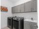 Modern laundry room with gray cabinets, laundry sink and a washer and dryer at 19283 Allium Pl, Orlando, FL 32827