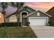 Charming home with a well-manicured lawn, palm trees, and two-car garage at sunset at 2735 Lido Key Dr, Kissimmee, FL 34747