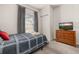 Cozy bedroom with a single bed, dresser with television and a window with gray curtains at 2903 Edenshire Way # 103, Kissimmee, FL 34746