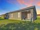 The backyard features a covered patio, sliding glass doors, a well-manicured lawn, and sunset sky at 3105 Sangria St, Kissimmee, FL 34744