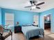 Light blue bedroom with two windows, ceiling fan, and wood look flooring leading into the ensuite bathroom at 3105 Sangria St, Kissimmee, FL 34744