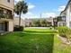 A serene view of the backyard showcases a lush lawn, complemented by a volleyball court, and palm trees at 4215 S Semoran Blvd # 15, Orlando, FL 32822