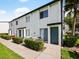 Inviting exterior featuring a well-maintained white townhome with a green door and manicured shrubbery in a garden setting at 4215 S Semoran Blvd # 15, Orlando, FL 32822
