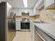 Modern kitchen featuring stainless steel appliances, white cabinets, and marble-style countertops with a mosaic backsplash at 4215 S Semoran Blvd # 15, Orlando, FL 32822