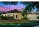 Inviting home with a well-manicured lawn, lush landscaping, and a charming front entrance at twilight at 506 Alleria Ct, Auburndale, FL 33823