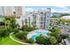 View of condo's pool and landscaping, with a lakeside building nearby offering recreation and natural beauty at 6165 Carrier Dr # 1603, Orlando, FL 32819