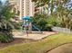Outdoor playground featuring a slide and climbing structure surrounded by lush landscaping and a fenced area at 6165 Carrier Dr # 1603, Orlando, FL 32819