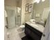 Well lit bathroom with a glass-door shower, granite countertop sink, and white tile flooring at 9055 Dogleg Dr, Davenport, FL 33896