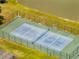 Aerial view of a fenced tennis court with a blue surface, situated near a pond and green lawn at 997 Lake Berkley Dr, Kissimmee, FL 34746