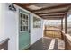 Covered back porch with railing, wooden planks and an exterior door with glass panes at 1018 Jersey Ave, St Cloud, FL 34769