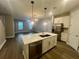 Open-concept kitchen and living area, featuring a large island, stainless steel appliances, and contemporary lighting at 12253 S Bracco St, Winter Garden, FL 34787