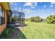 Spacious backyard with lush lawn, screened-in lanai, and view of palm trees at 130 Los Gatos Pl, Kissimmee, FL 34759