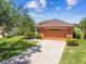 Charming single-story home boasts an orange garage door, lush lawn, and a paver driveway at 130 Los Gatos Pl, Kissimmee, FL 34759