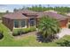 Landscaped front yard with a palm tree and a two-car garage on a sunny day at 130 Los Gatos Pl, Kissimmee, FL 34759