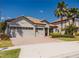 Charming single-story home featuring a three-car garage, tile roof, and well-manicured landscaping under a sunny blue sky at 1302 Moss Creek Ln, Davenport, FL 33896