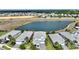 Aerial view of a modern home next to a pond surrounded by lush landscaping in a vibrant community at 1443 Bunker Dr, Davenport, FL 33836