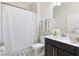 Clean bathroom with dark wood vanity, shower with white curtain, and decorative accents at 1443 Bunker Dr, Davenport, FL 33836