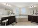 Bright bathroom features double vanity, tiled floors, a soaking tub with corner windows at 1443 Bunker Dr, Davenport, FL 33836