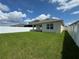 Expansive backyard featuring green grass, a white vinyl fence, and a covered patio at 1648 Heart Bar Rd, Kissimmee, FL 34744