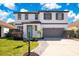Charming two-story home featuring a well-maintained lawn, a two car garage, and an inviting entrance at 227 Sand Ridge Drive, Davenport, FL 33896