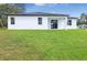 A modern white home features an expansive backyard, and a covered patio with sliding glass doors at 2437 Sw 147Th Ln, Ocala, FL 34473