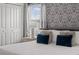 Comfortable bedroom with a patterned accent wall, soft pillows, and a view to the outside at 2605 Reading Trl, Kissimmee, FL 34746