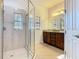 Bright bathroom featuring a tiled walk-in shower with glass door and wood vanity with marble countertop at 343 Scripps Ranch Rd, Poinciana, FL 34759