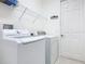 Bright laundry room with white washer and dryer, shelving, and a door at 343 Scripps Ranch Rd, Poinciana, FL 34759