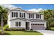 Two story home with gray siding, black shutters, stone accents, and a two car garage on a well-manicured lawn at 4084 Bannock Ave, Tavares, FL 32778