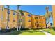 Bright yellow three-story apartment building featuring manicured landscaping, sidewalks and palm trees at 4528 Commander Dr # 2013, Orlando, FL 32822