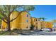 Bright yellow three-story apartment building with on-site parking and mature trees on a sunny day at 4528 Commander Dr # 2013, Orlando, FL 32822