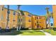 Bright yellow three-story apartment building featuring manicured landscaping, sidewalks and palm trees at 4528 Commander Dr # 2013, Orlando, FL 32822