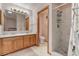 Bathroom with double sinks, wooden cabinets, and a walk-in shower with white marble tile at 508 Alcazar Ct, The Villages, FL 32159