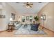 Cozy living room with vaulted ceilings, a ceiling fan, wood-look flooring, and natural light from large windows at 508 Alcazar Ct, The Villages, FL 32159
