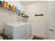 Functional laundry room with modern washer and dryer units and storage shelves for organization at 5759 Marsh Landing Dr, Winter Haven, FL 33881