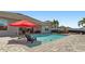 Inviting backyard pool featuring a red umbrella and lounge chairs for relaxation and a brick-paved deck at 5759 Marsh Landing Dr, Winter Haven, FL 33881