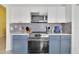 Updated kitchen with stainless steel appliances, white countertops, and blue lower cabinets at 577 Eagle Pointe S, Kissimmee, FL 34746
