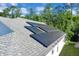 An aerial view of a roof featuring mounted solar panels and mature trees at 577 Eagle Pointe S, Kissimmee, FL 34746